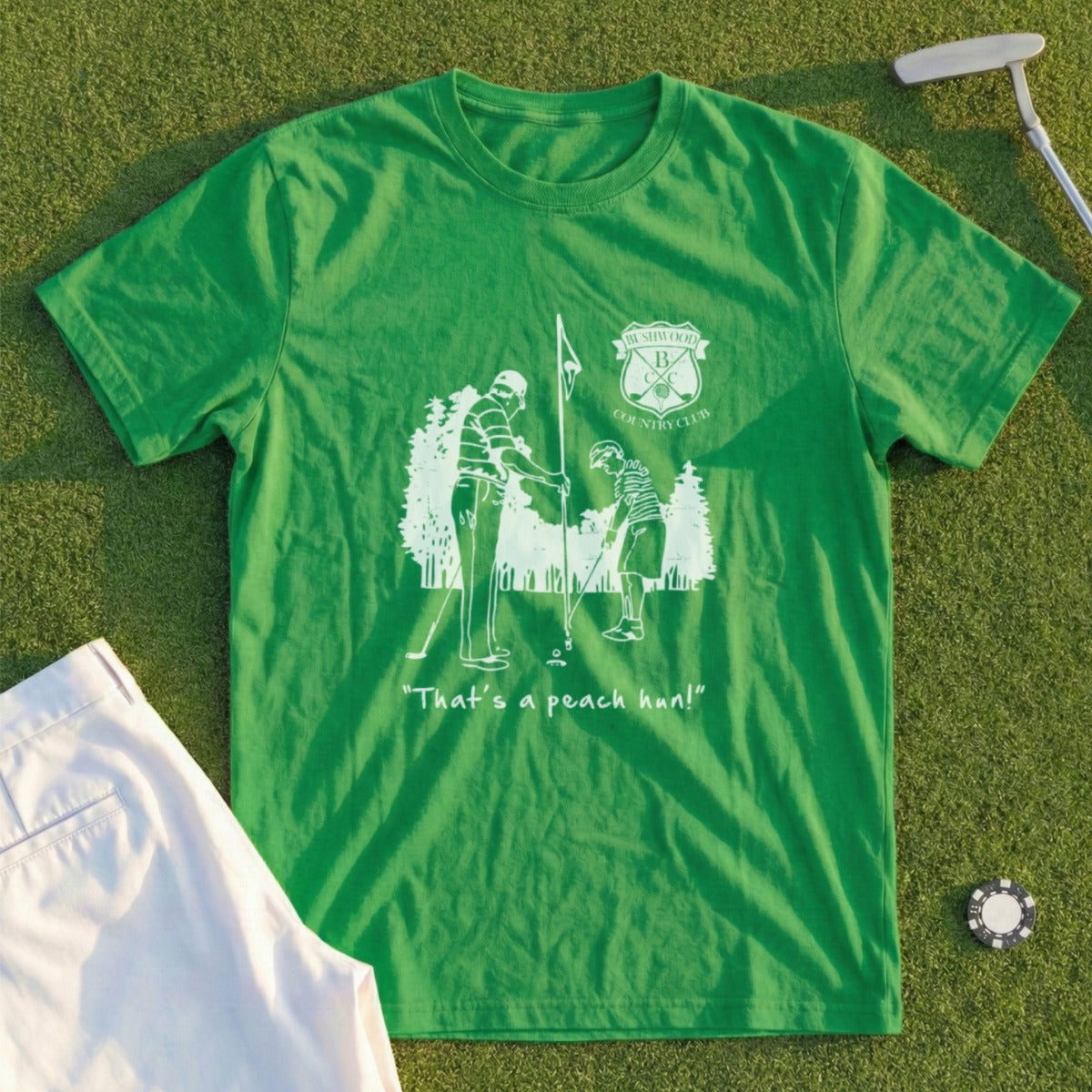 Green t-shirt with golf club logo and cartoon golfers, "That's a peach bun!"