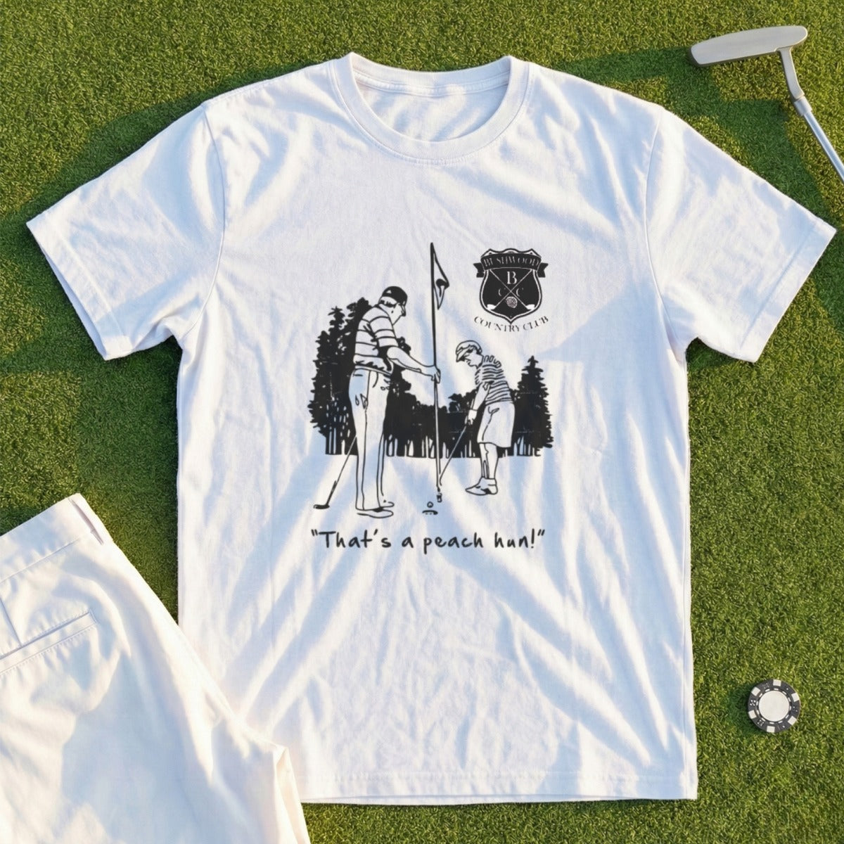 White t-shirt with black graphic of golfers and "That's a peach, hun!" text.