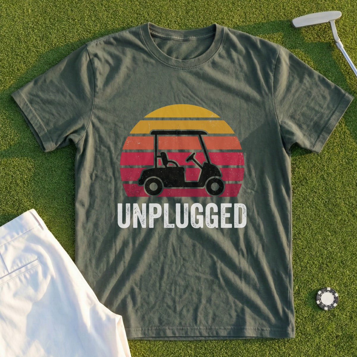 Green t-shirt with "UNPLUGGED" text and a golf cart silhouette within a sunset graphic.