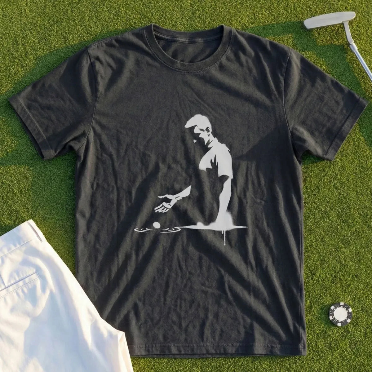 Dark t-shirt with silhouette of golfer dropping ball on green grass.