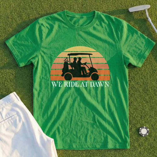 Green t-shirt with "WE RIDE AT DAWN" and golf cart sunset graphic.
