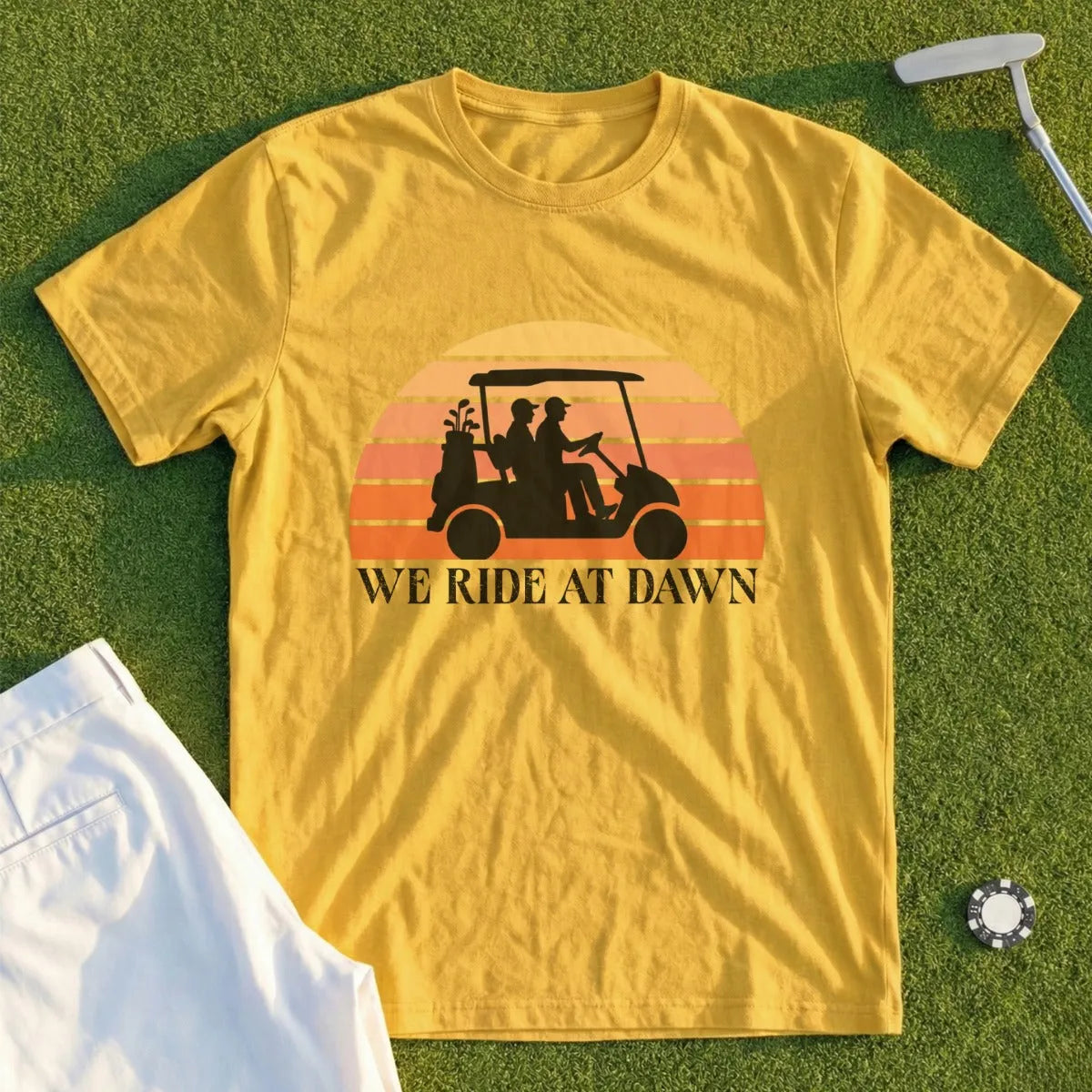 Yellow t-shirt with graphic of golfers in a cart at sunset and text "We Ride At Dawn".