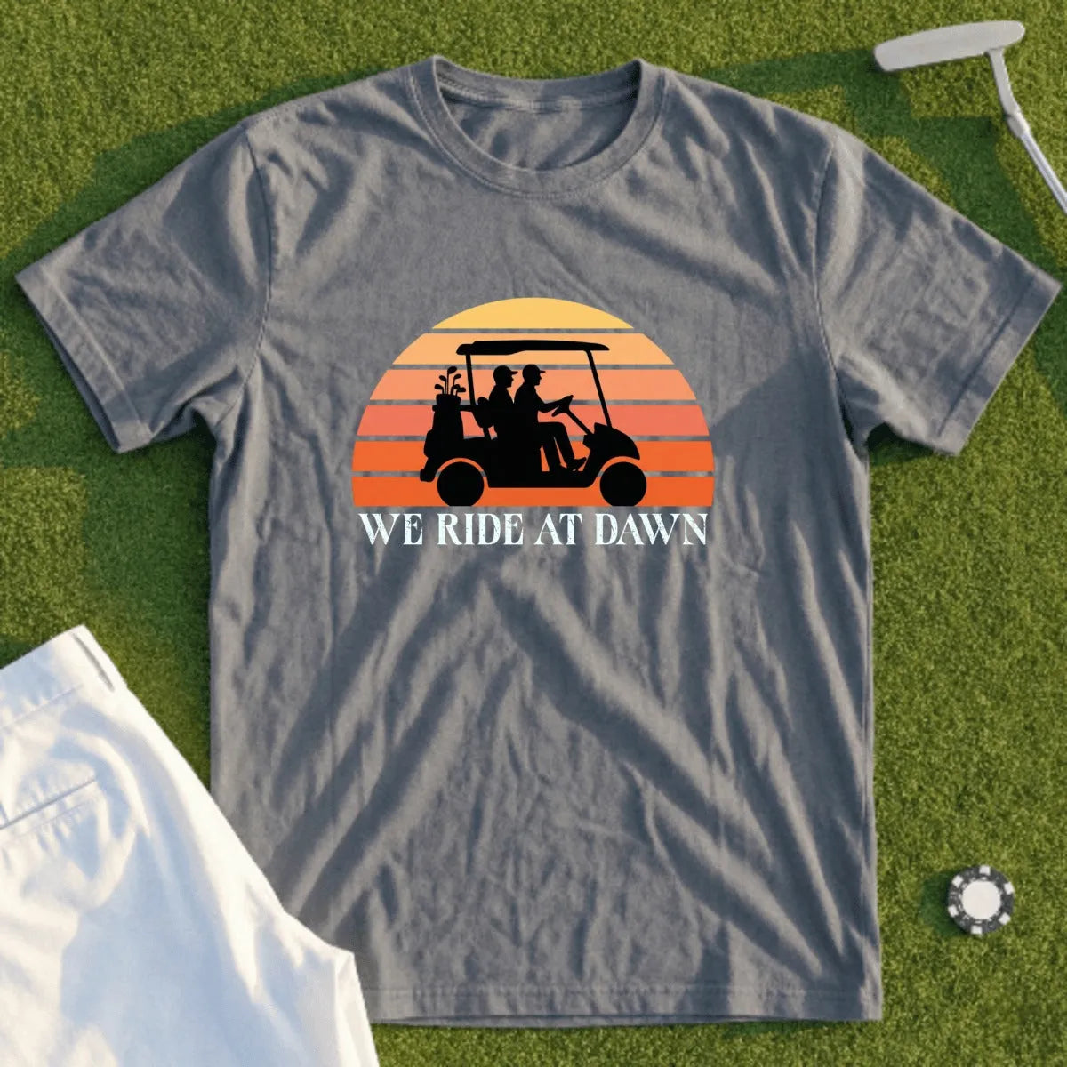 Gray t-shirt with "WE RIDE AT DAWN" and golf cart graphic at sunset.