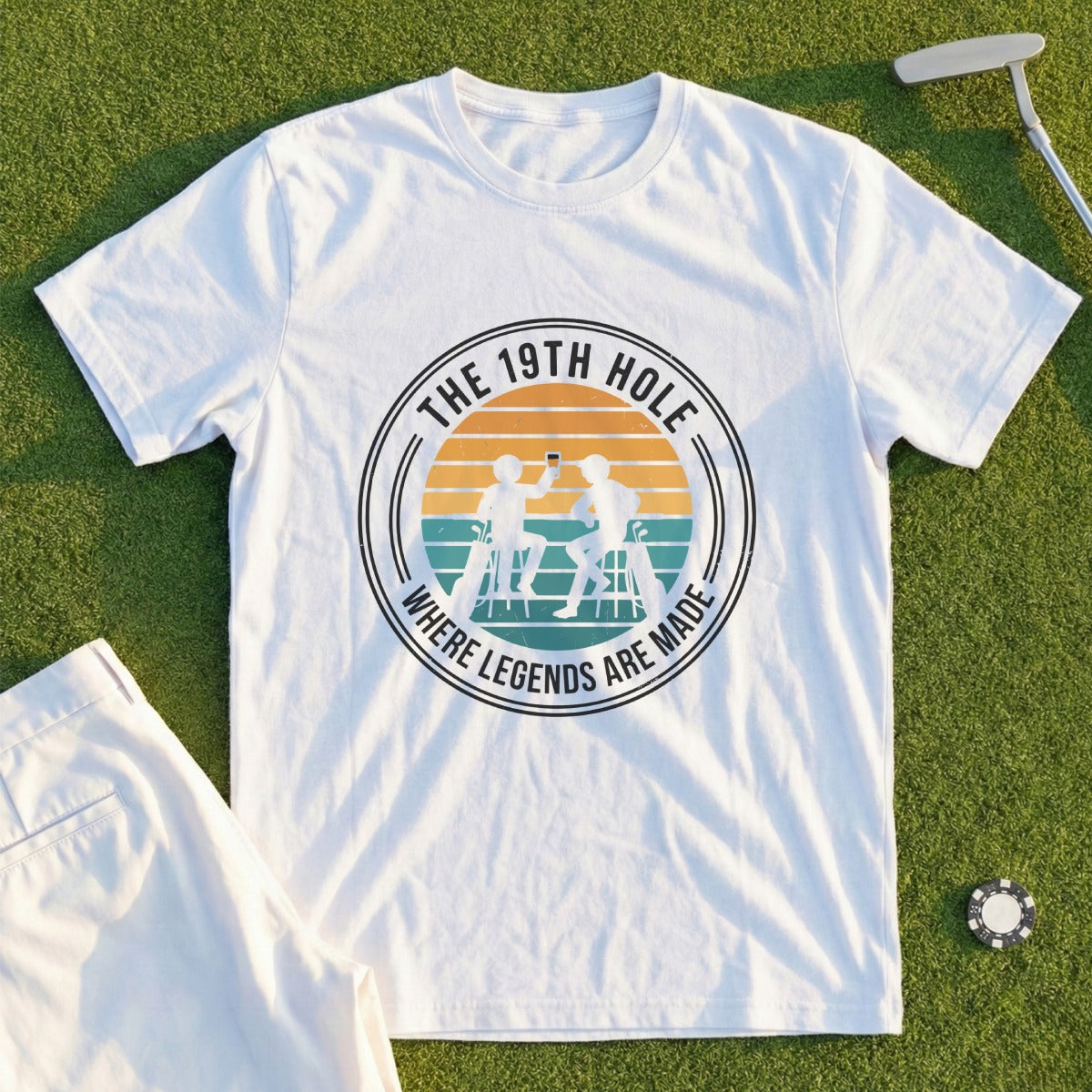 White t-shirt with "The 19th Hole: Where Legends Are Made" graphic.