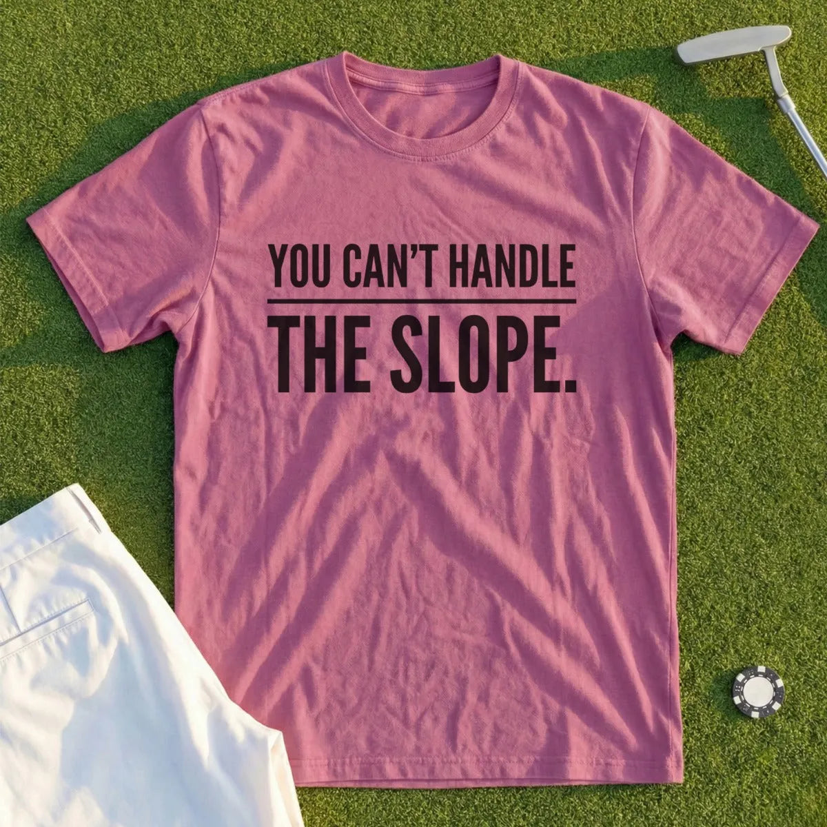 Pink t-shirt with black text "YOU CAN'T HANDLE THE SLOPE." on a golf course.