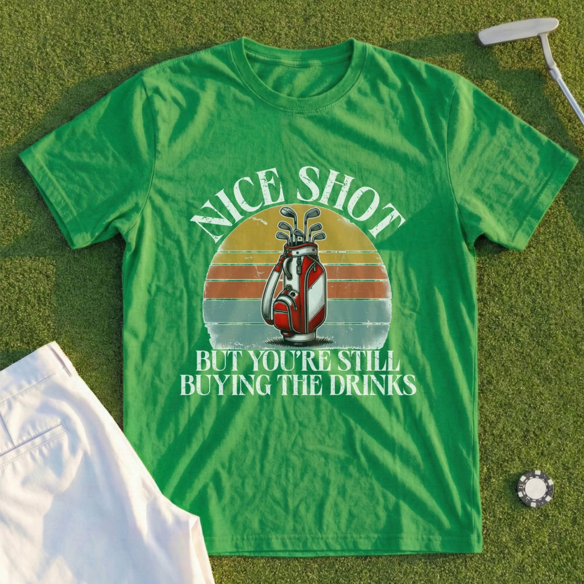 Green t-shirt with a golf graphic and the text "Nice Shot But You're Still Buying The Drinks".