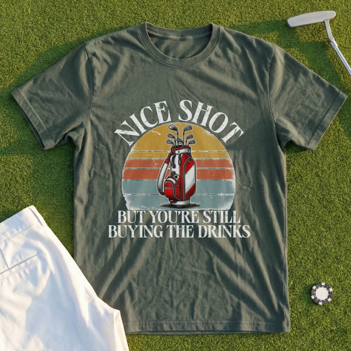 Green t-shirt with "Nice Shot But You're Still Buying The Drinks" and golf bag graphic.