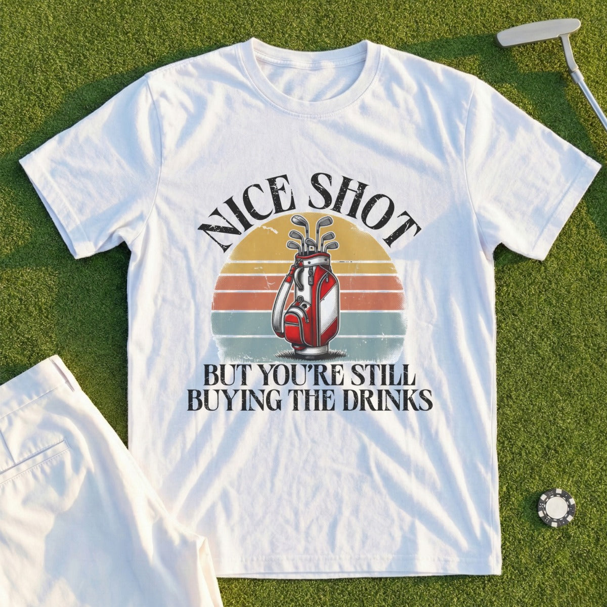 White t-shirt with "Nice Shot But You're Still Buying The Drinks" text and golf bag graphic.