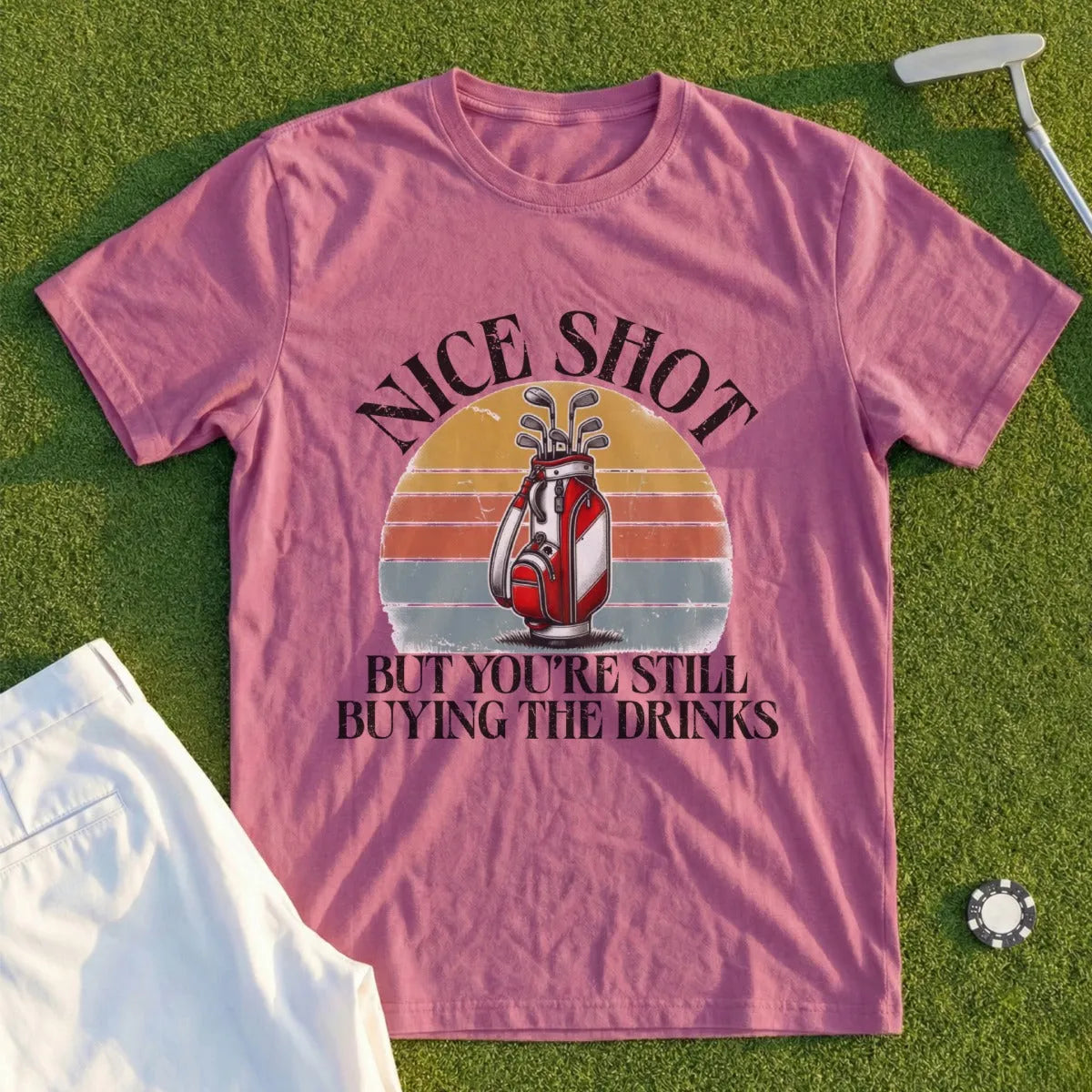 Pink t-shirt with "Nice Shot But You're Still Buying The Drinks" and golf bag graphic.
