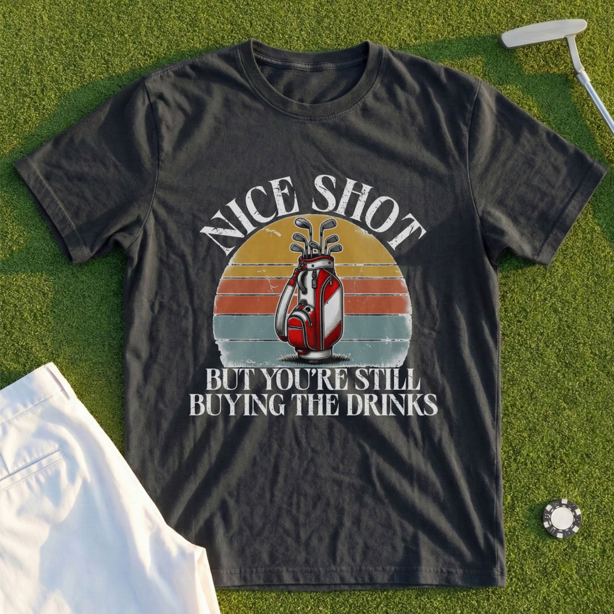Dark t-shirt with graphic: "Nice Shot But You're Still Buying The Drinks" and a golf bag.